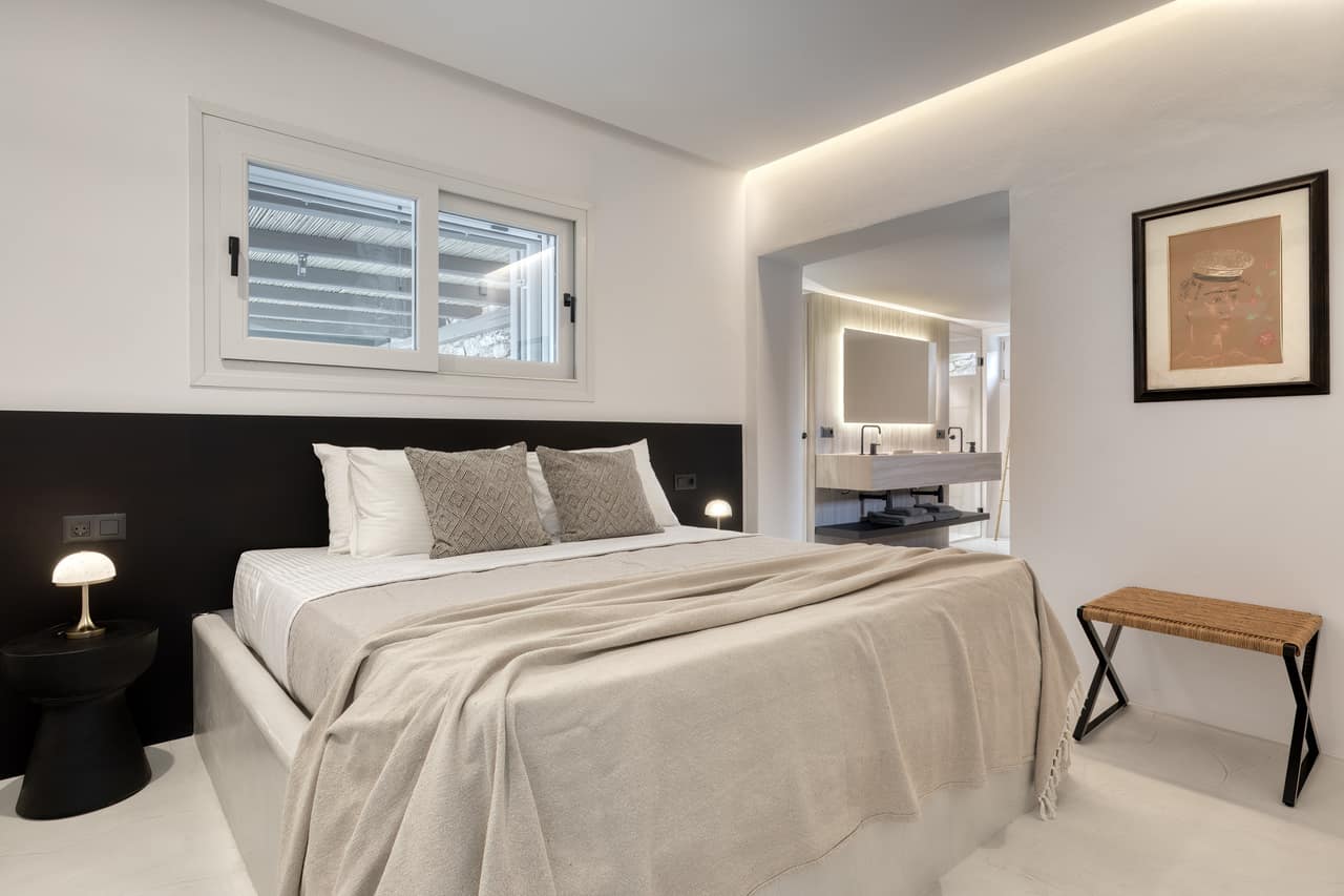 A bedroom open to its en suite, a black headboard and linen