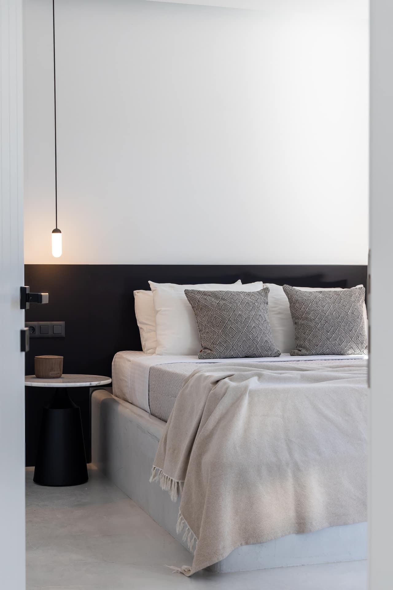 The main bedroom in pale plaster and linen, the hillside through the window