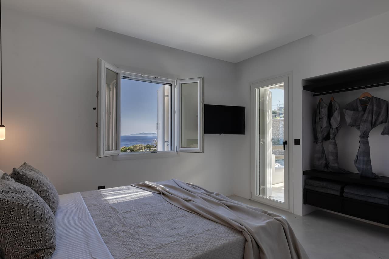 A bedroom with the window thrown open to the Aegean