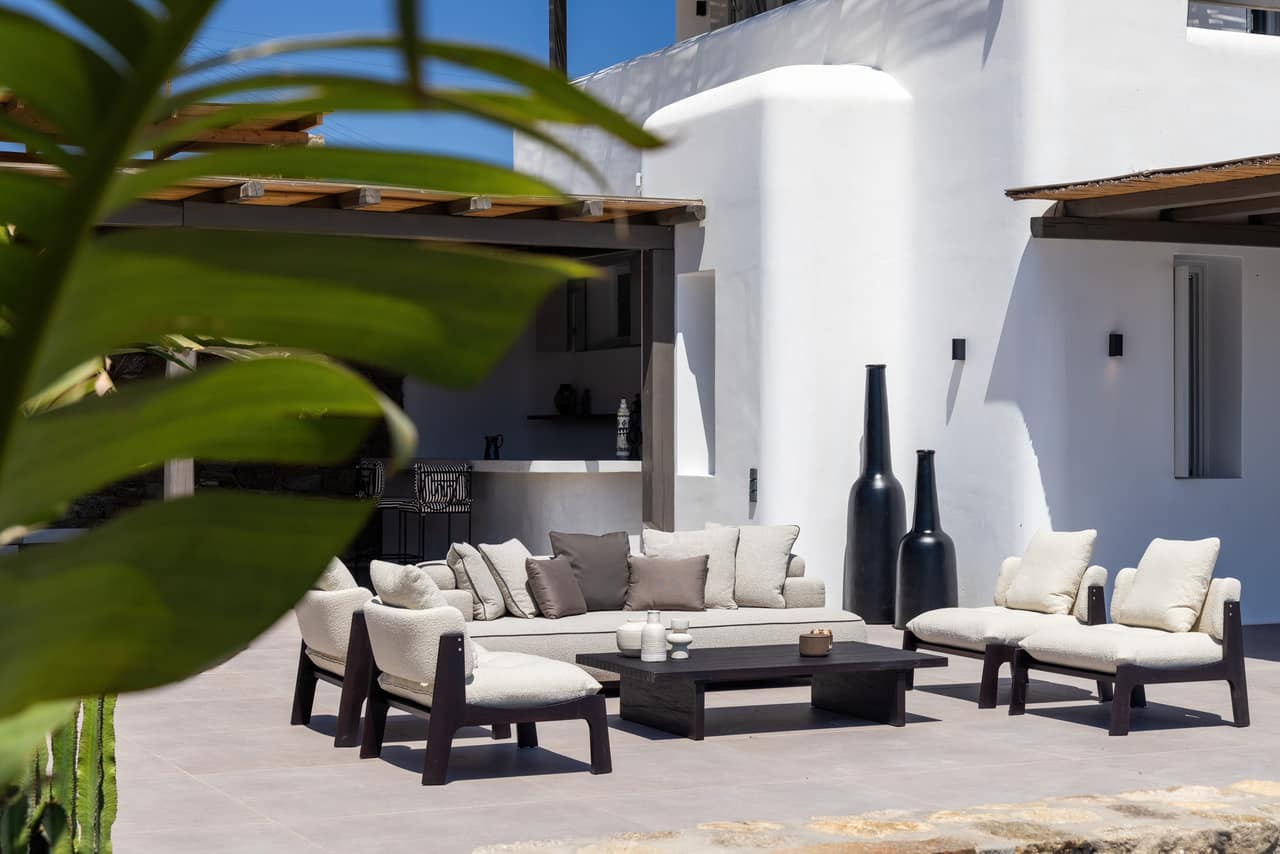 An outdoor lounge against the villa's white walls, dark beads and palm