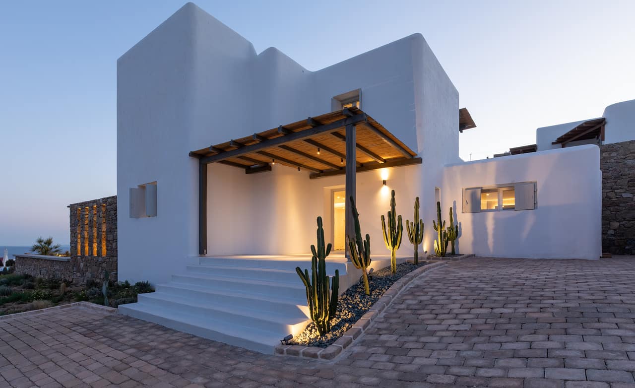The dining pergola at dusk, lamps lit, the pool quiet alongside