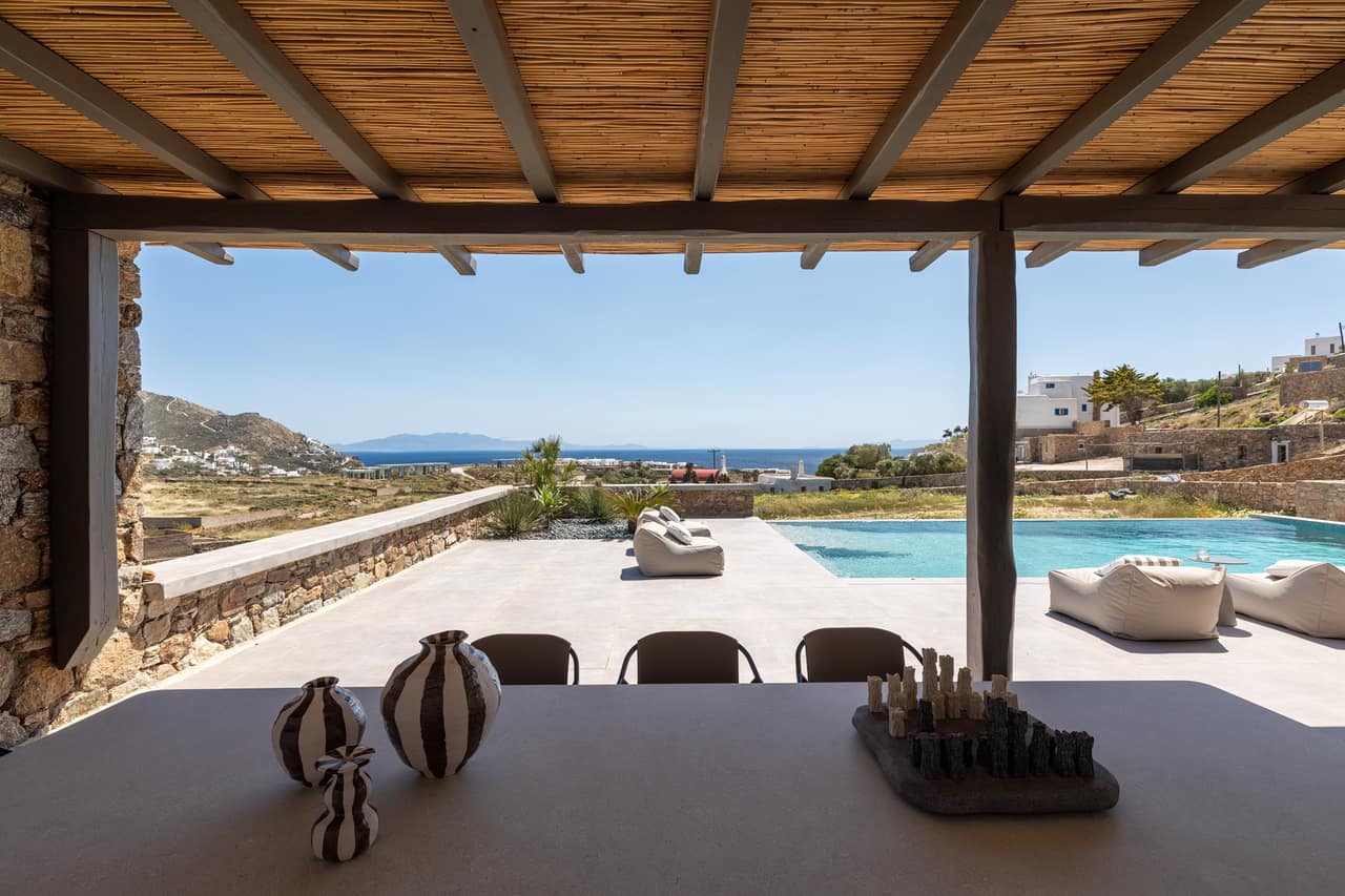 The dining table under the pergola, looking out to the pool and sea