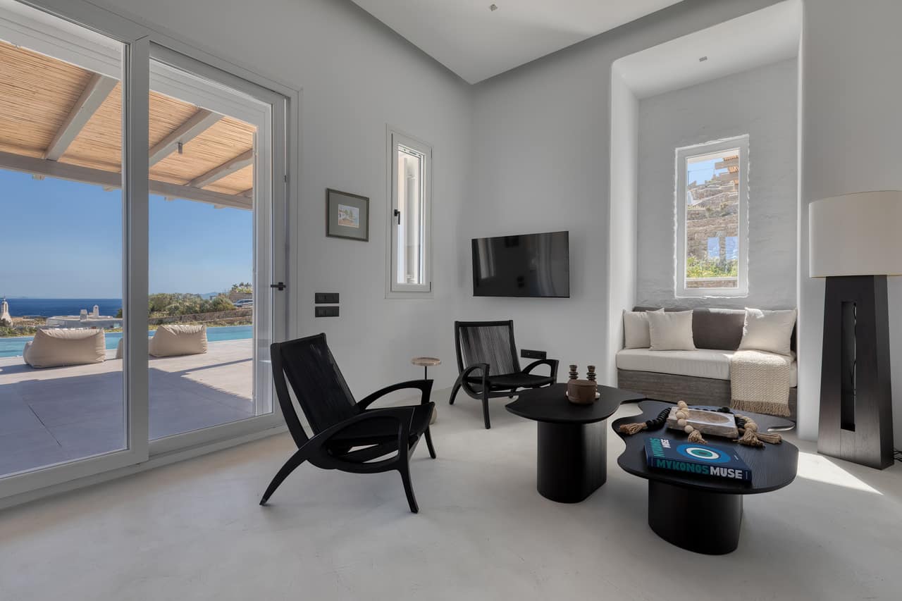 Black lounge chairs in the living room, terrace doors onto the pool