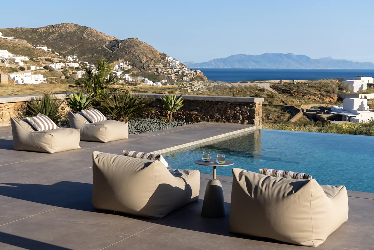 Low lounge chairs at the pool, the village and sea on the horizon