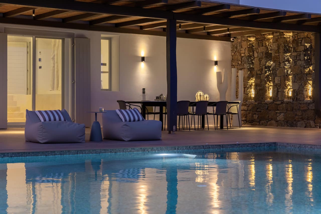 The pool after dark, the stone wall and pergola lit from within
