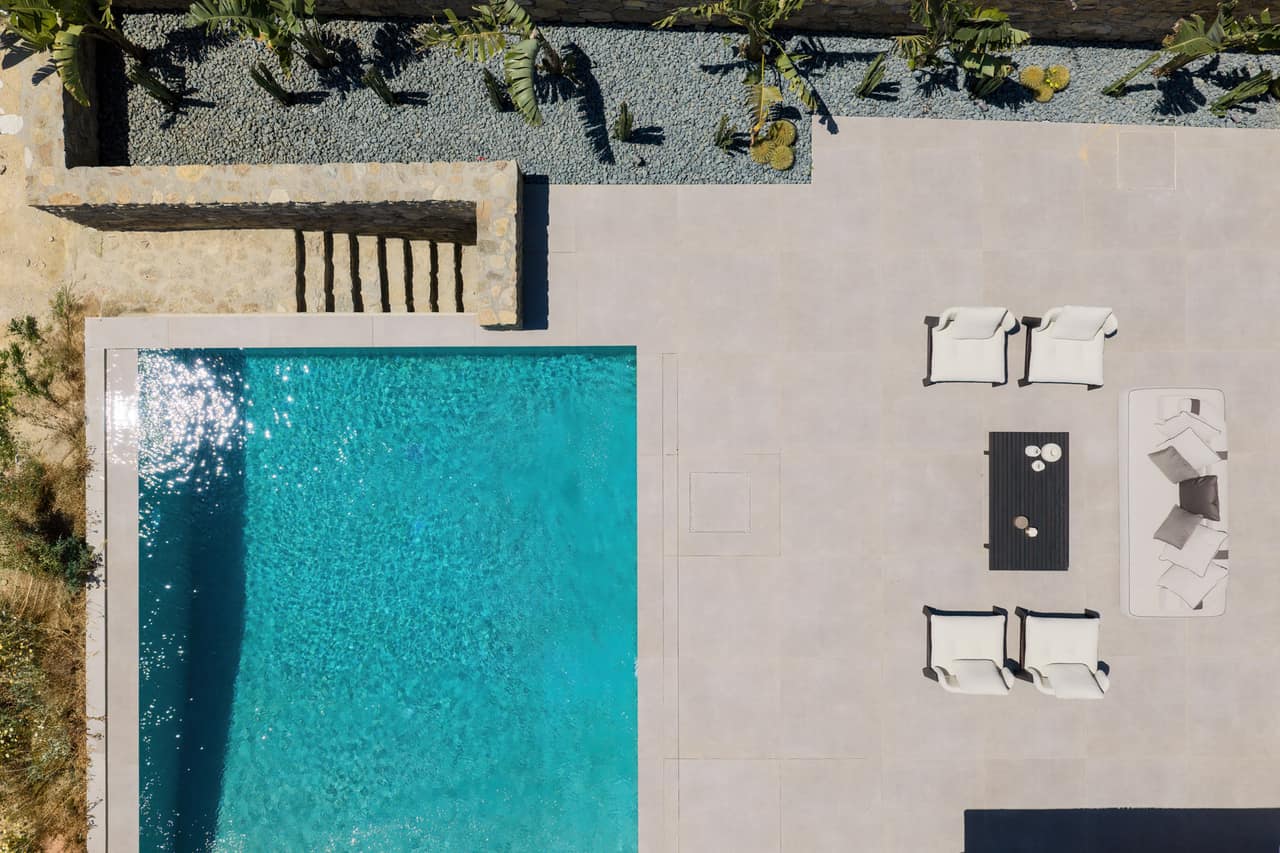 The pool terrace from above — water, loungers, dry-stone walls