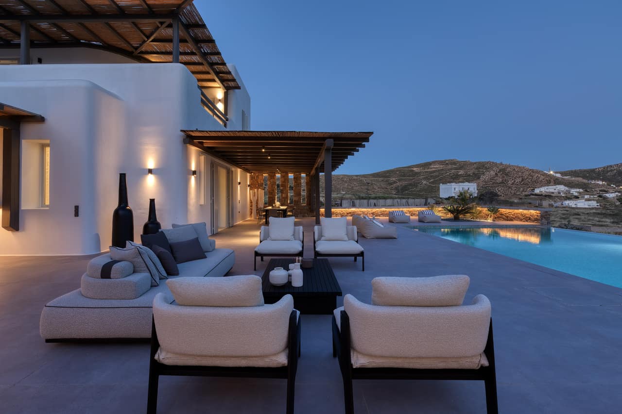 The terrace at blue hour — lit lounges, the pool, the darkening sea